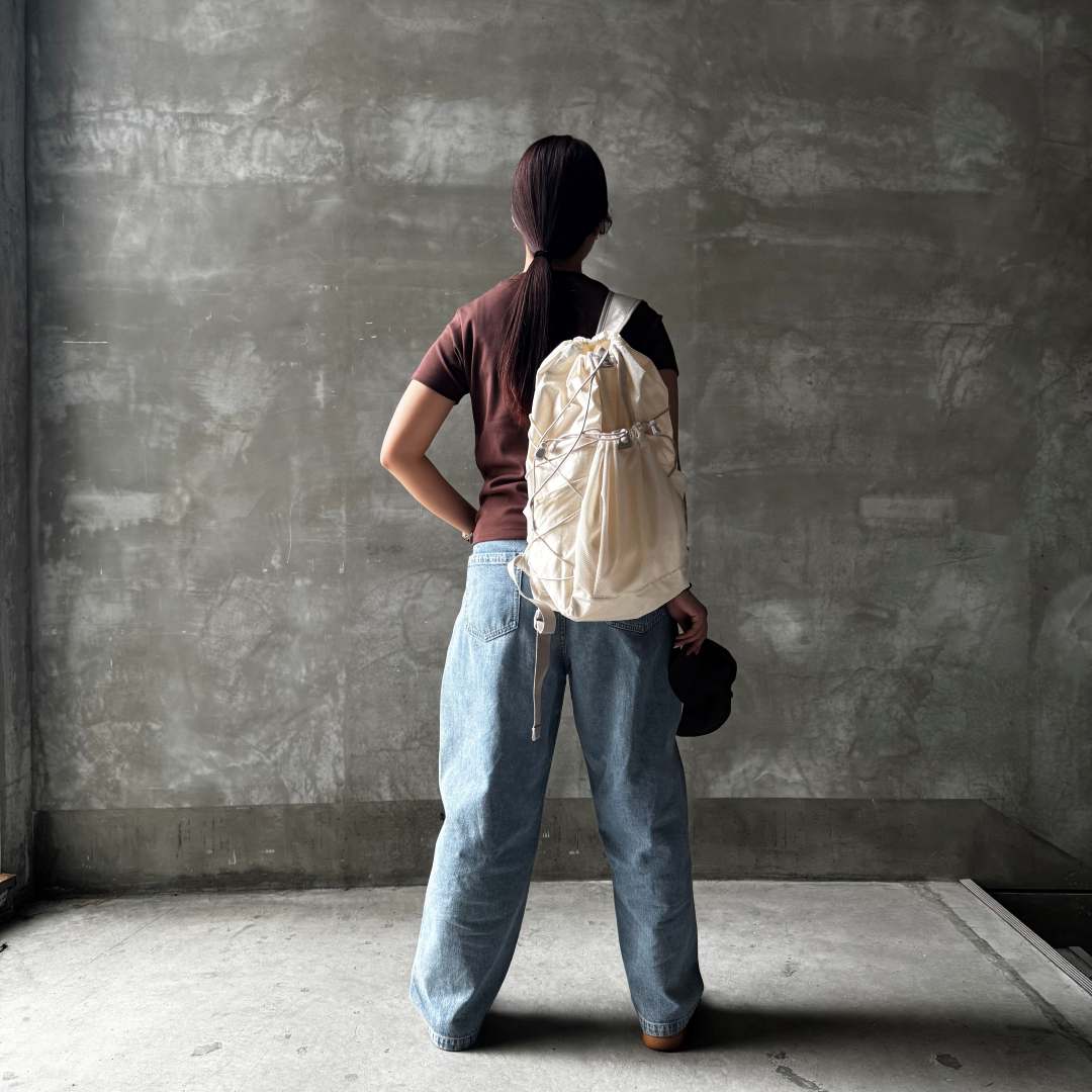 ブラウンのTシャツに白いリュックサックを持った女性の画像