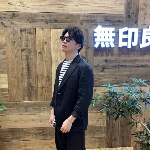 リネン素材のセットアップを着てサングラスをかけて立つ男性