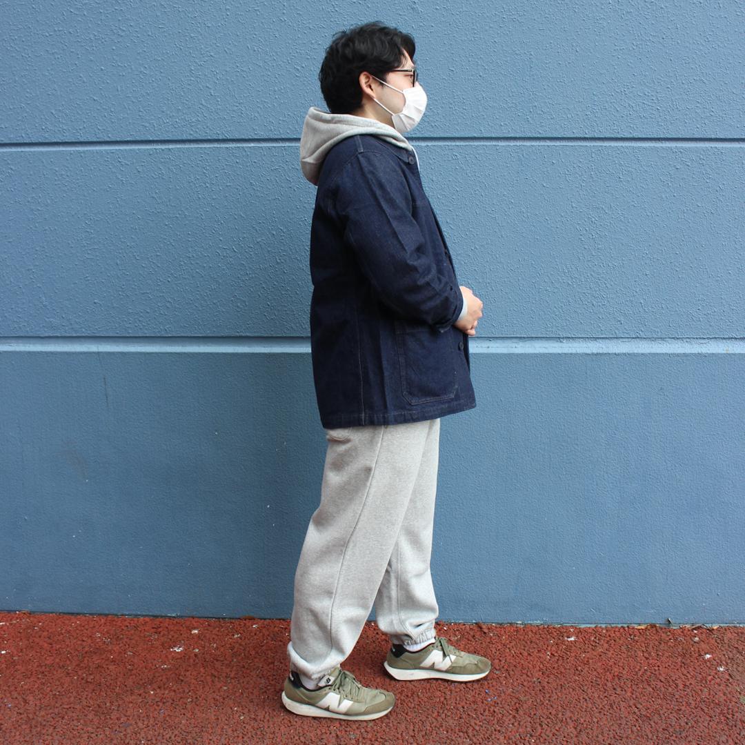 スウェットのセットアップにデニムのカバーオールを着たのを横から撮った写真