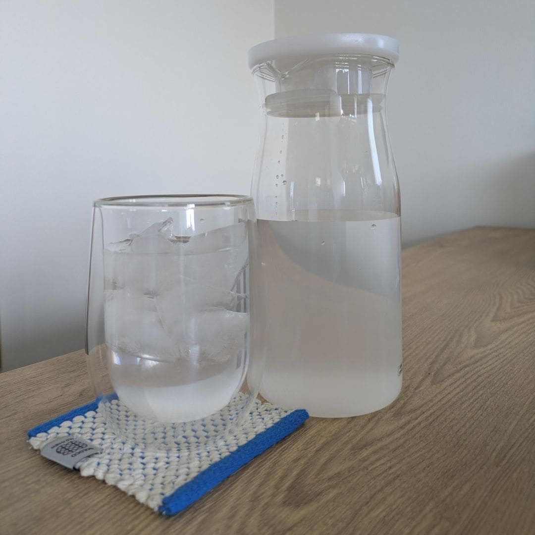 テーブルにコップとドリンクの入った容器の写真