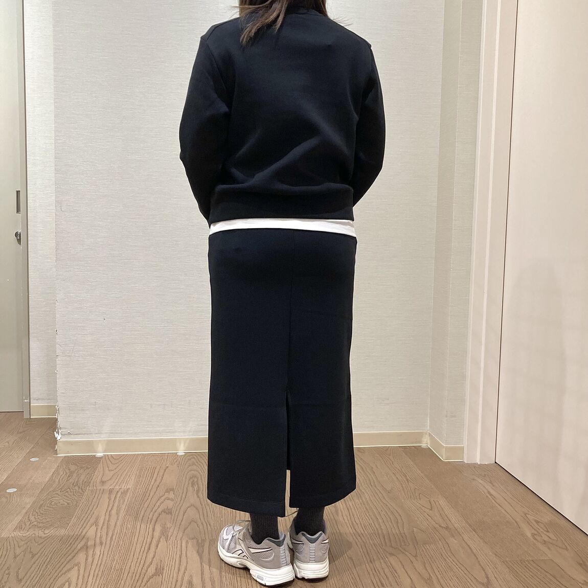 黒いスウェットのトップスとスカートを着用した女性