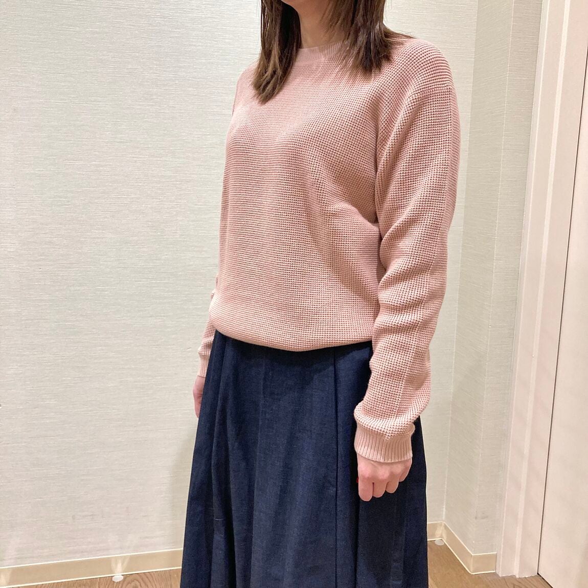 ピンクセーターとダークネイビーのスカートを着用した女性