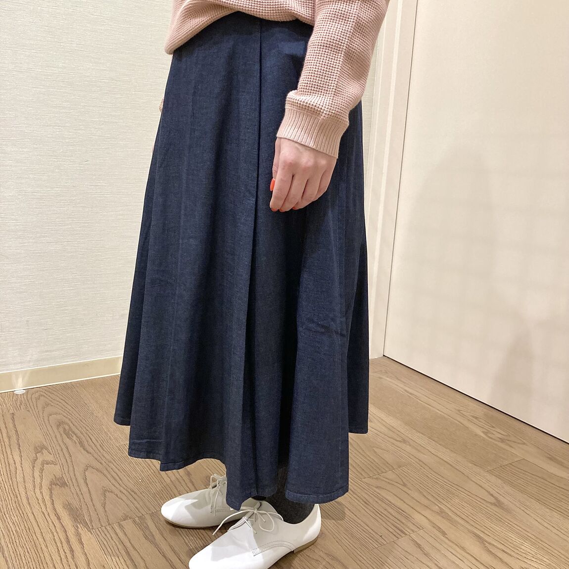 ピンクのセーターとダークネイビーのスカートを着用した女性