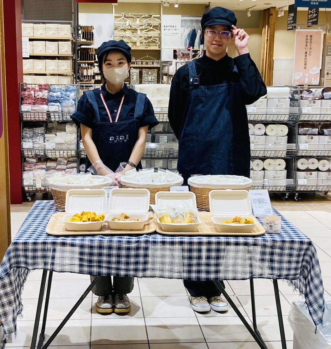 試食会の様子を表す画像です。スタッフ2名が試食品の提供を行っています。