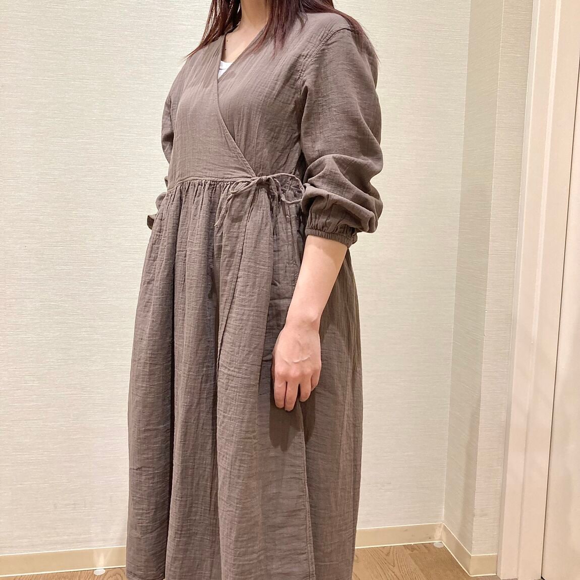 ブラウンのカシュクールワンピースを着用した女性