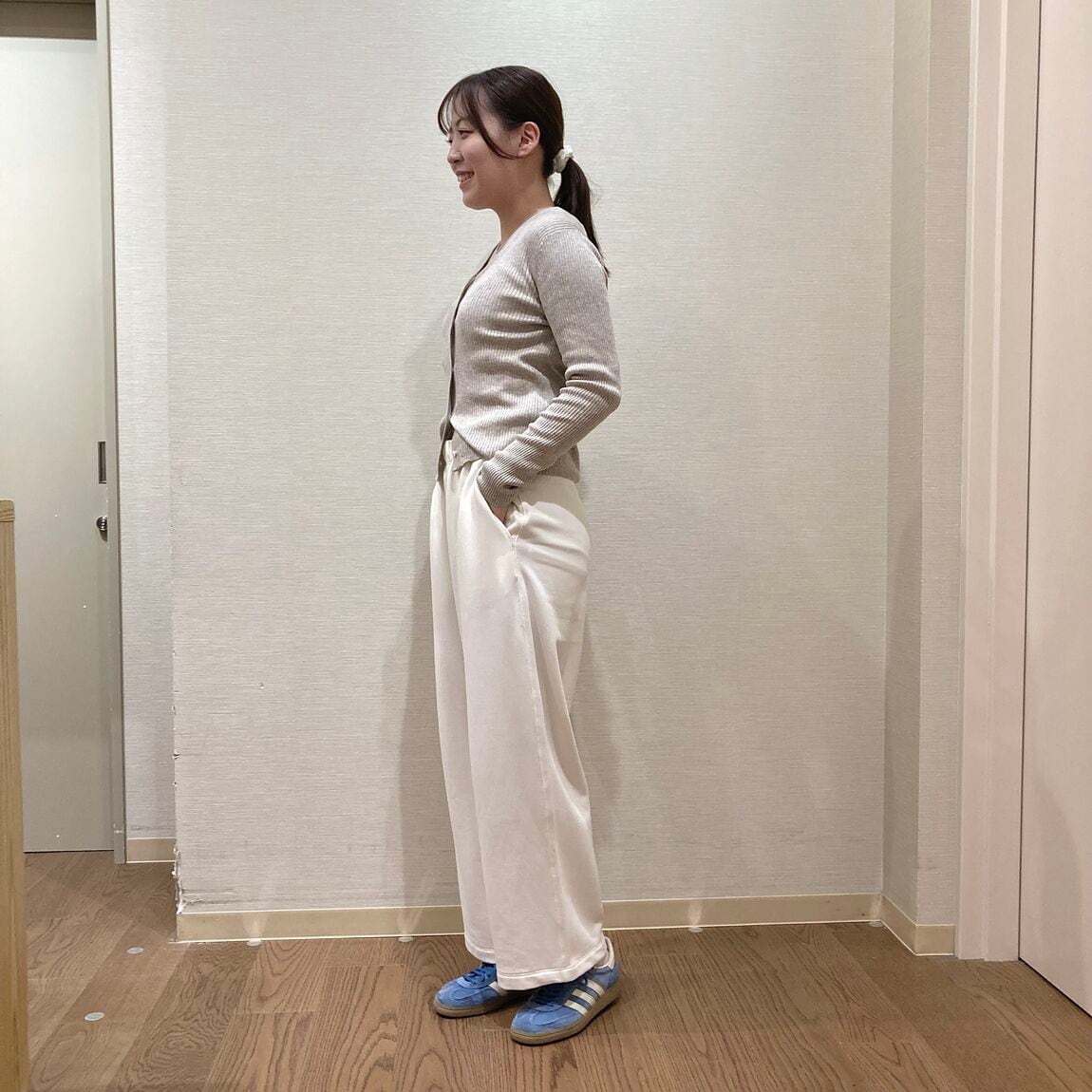 ベージュのカーディガンと白いスウェットパンツを着用した女性