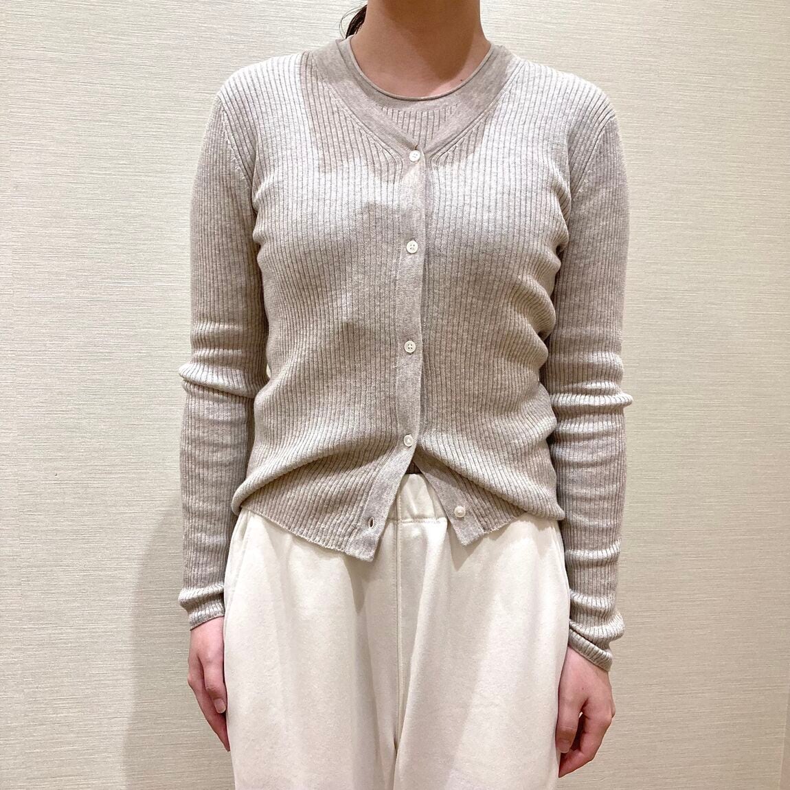 ベージュのカーディガンと白いスウェットパンツを着用した女性