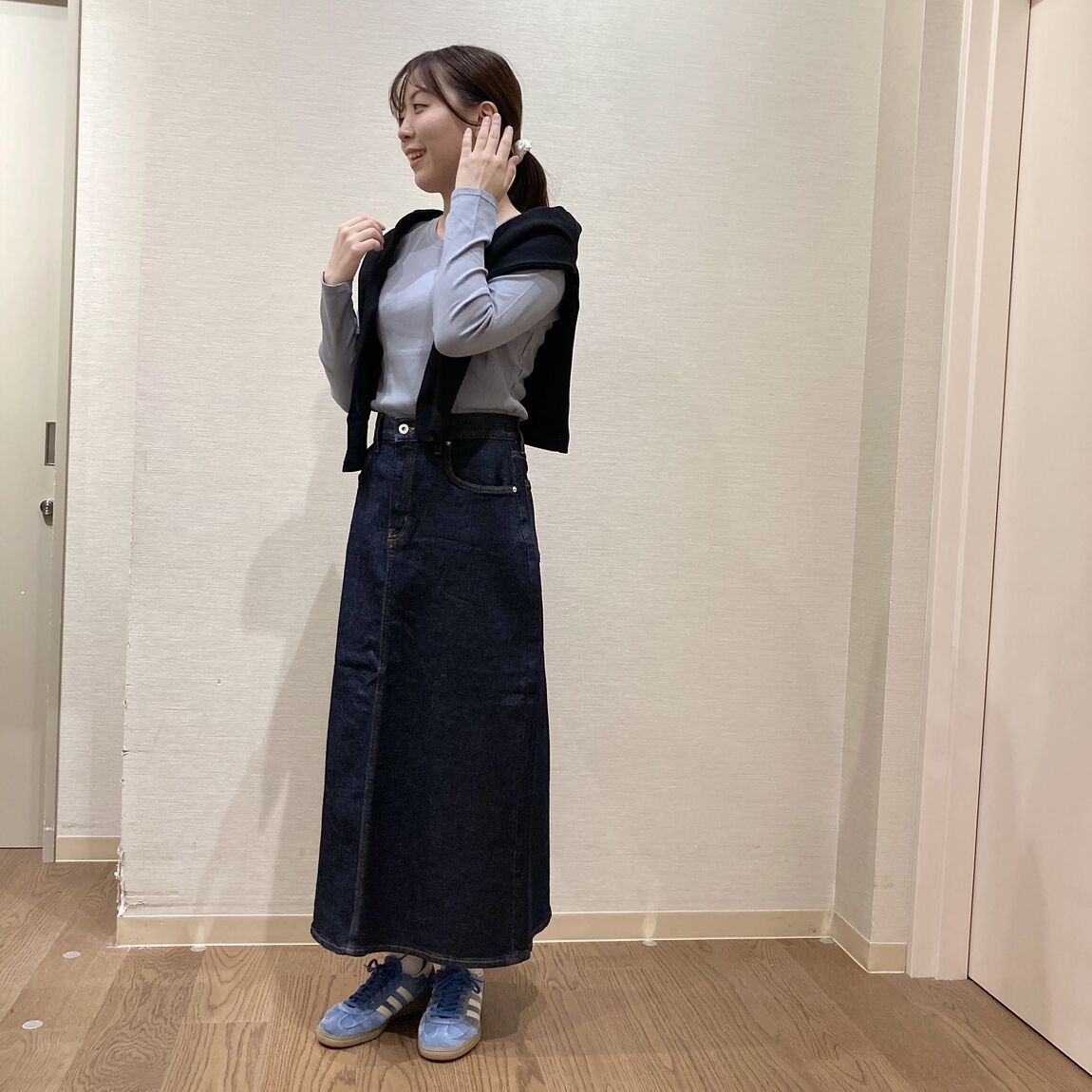 ライトブルーのトップスにデニムスカートを着用した女性