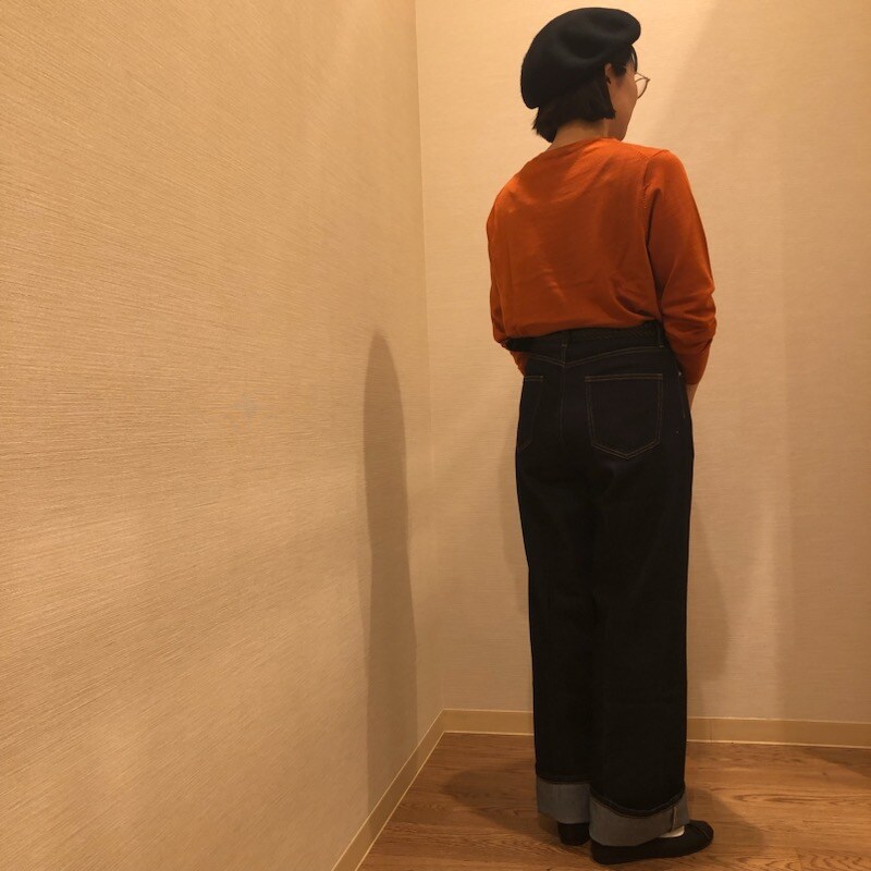 バギーデニムとレンガ色のクルーネックセーターを着用した女性の後ろ姿