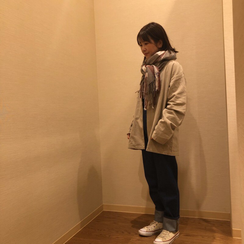 レギュラーデニムを履いてフランネルジャケットを着てマフラーを巻いた女性の写真