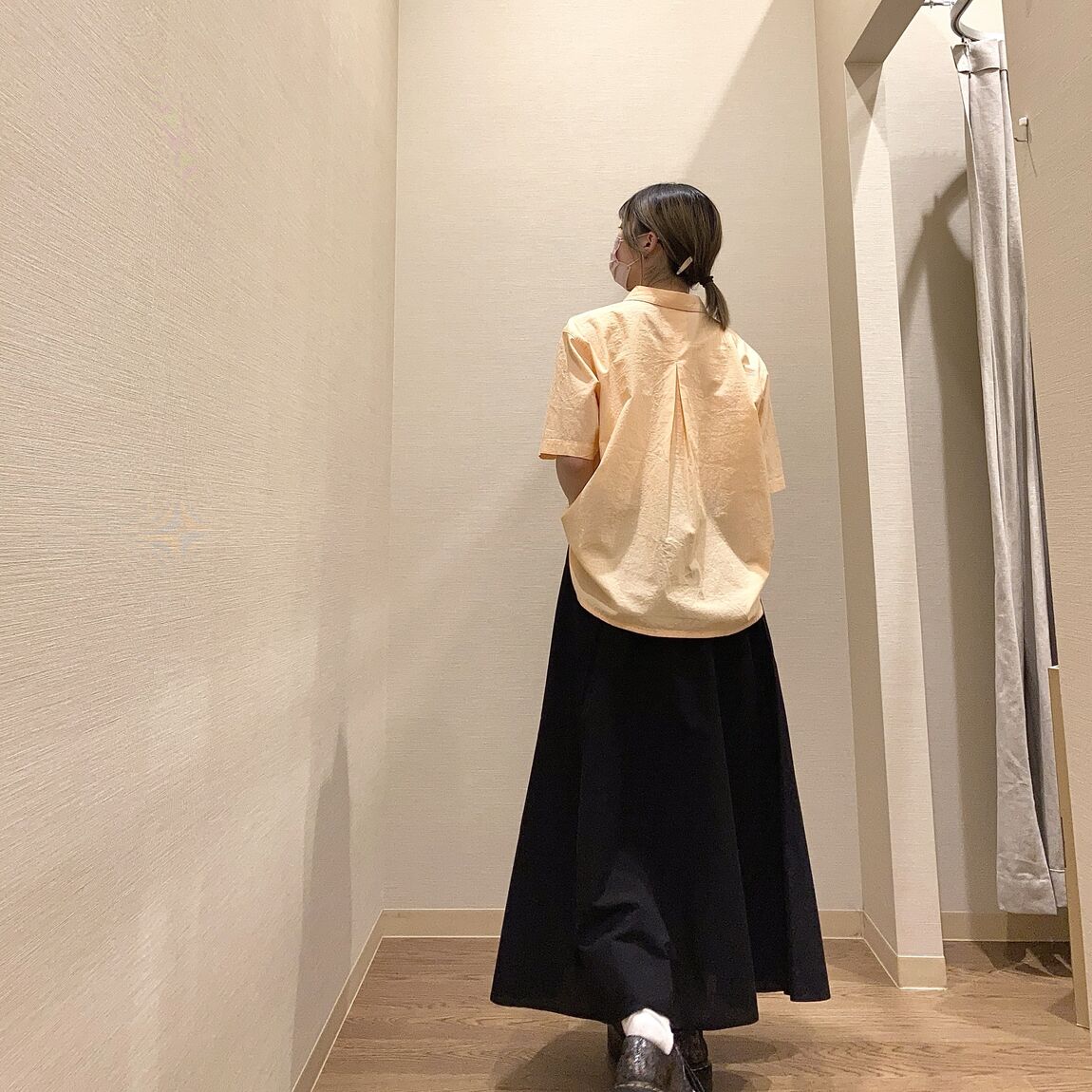 オレンジのシャツと黒のフレアスカートを着用した女性