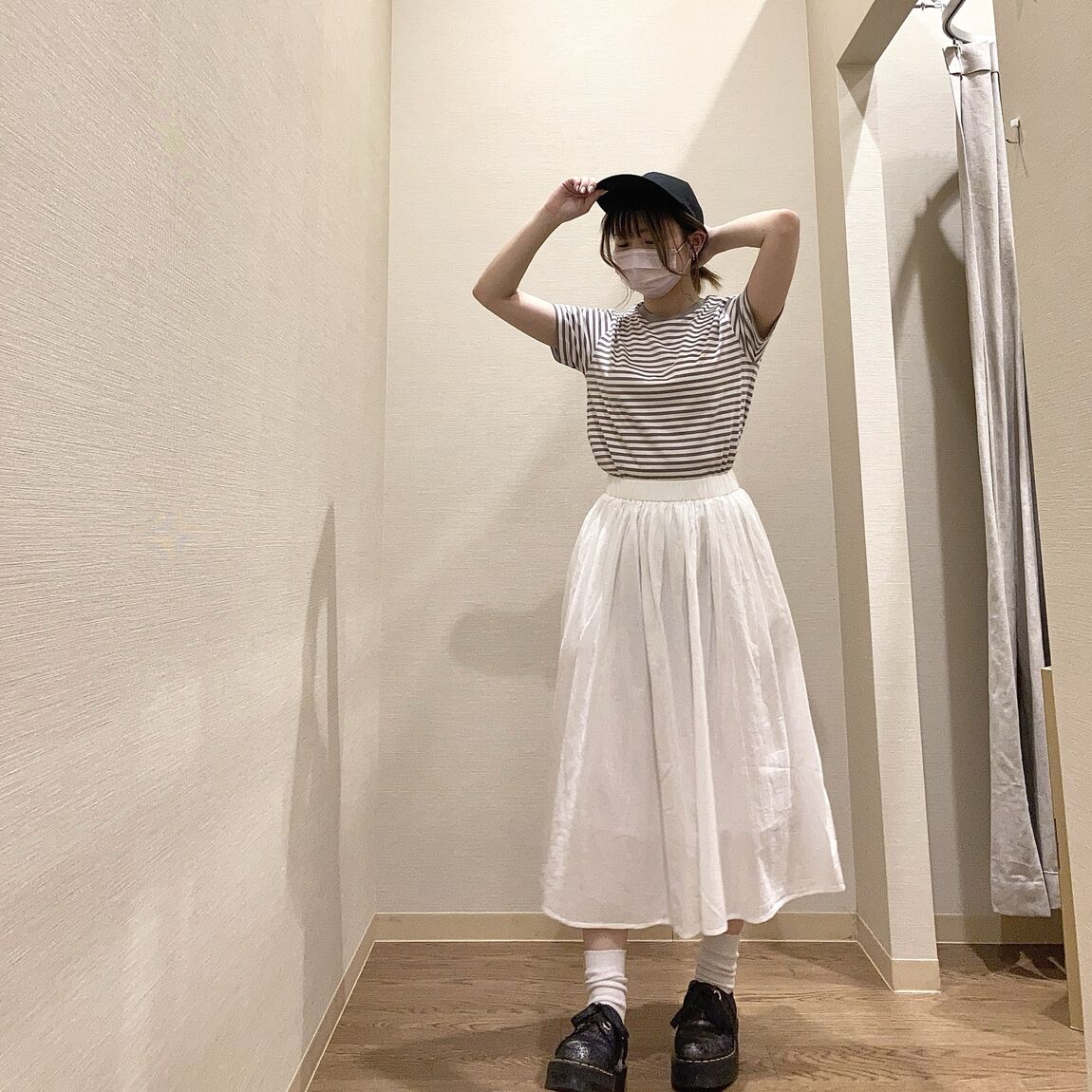 ボーダーのTシャツと白いスカートを着用した女性