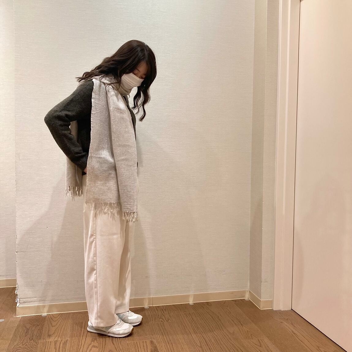 カーキのニットとベージュのマフラーを着用した女性