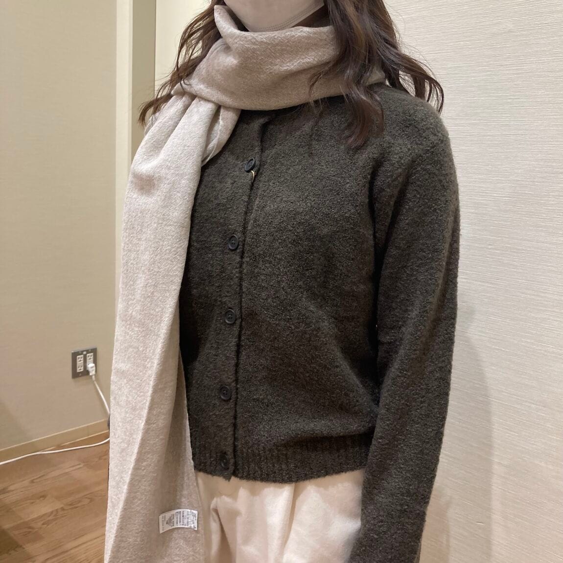 カーキのニットとベージュのマフラーを着用した女性