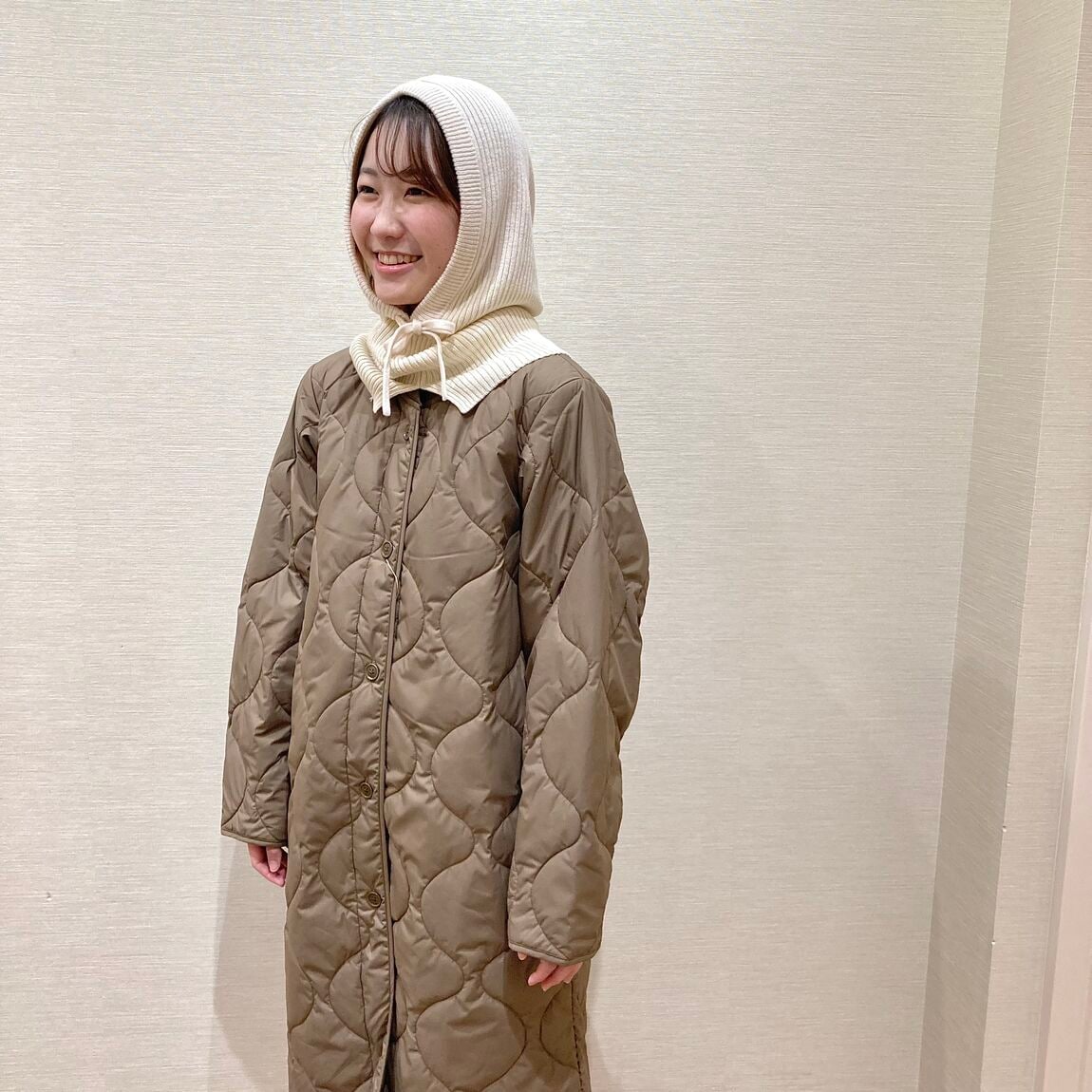 カーキのコートとアイボリーのバラクラバを着用した女性