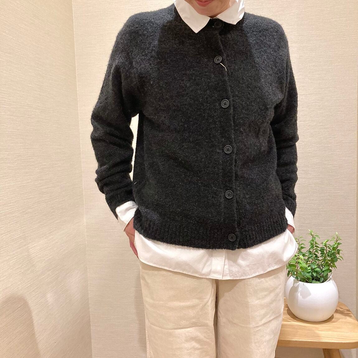 白のパンツとチャコールグレーのカーディガンを着用した女性