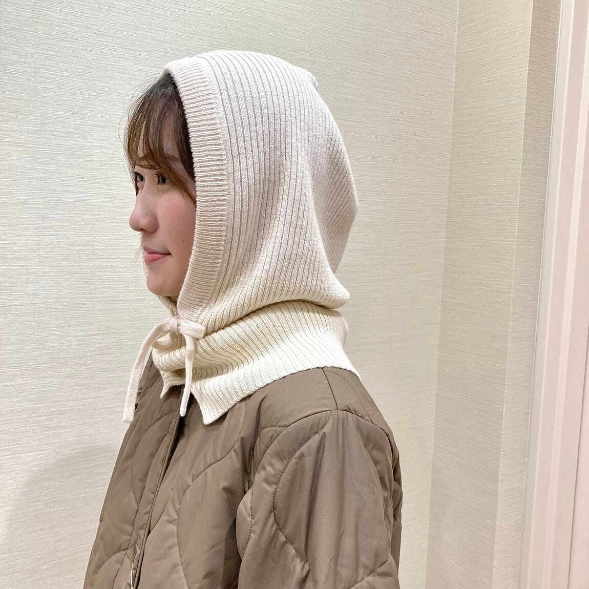 カーキのコートとアイボリーのバラクラバを着用した女性