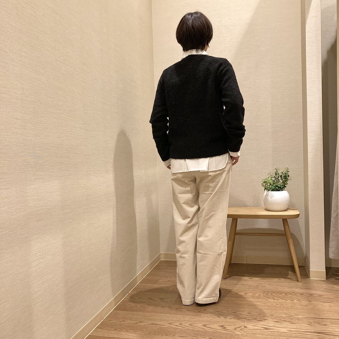 白いパンツとチャコールグレーのカーディガンを着用した女性