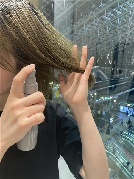 商品を髪にスプレーしている写真