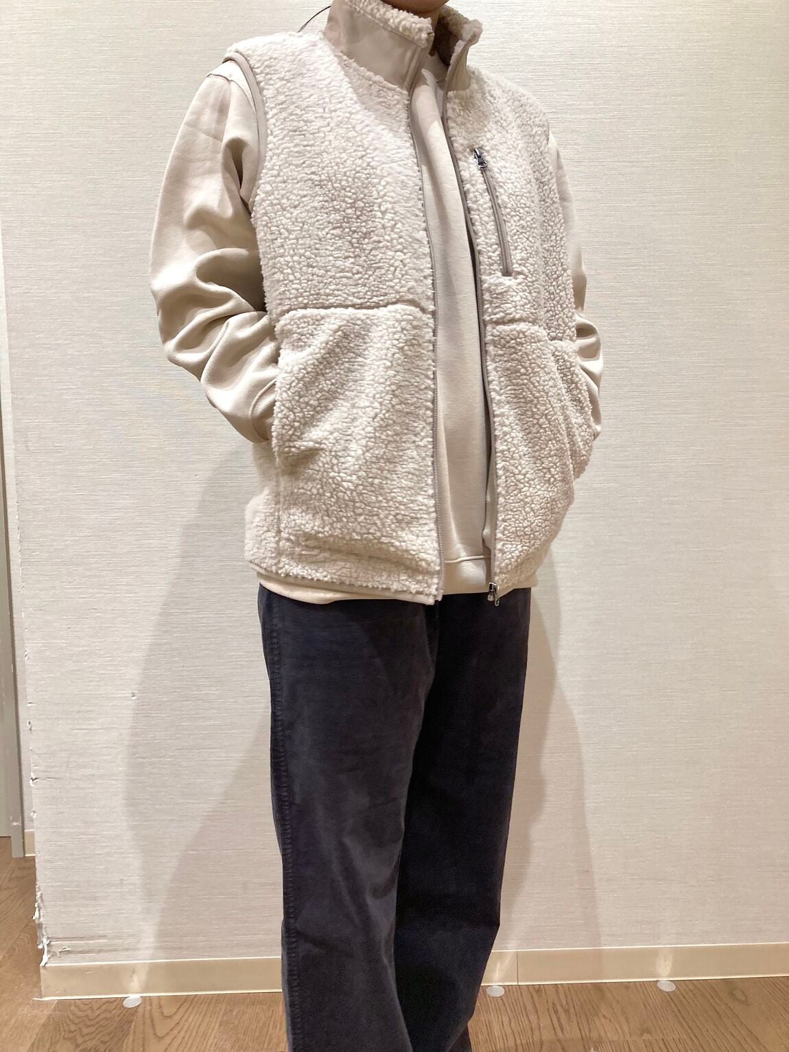 ベージュのスウェットシャツとベージュのボアベストを着用した女性　