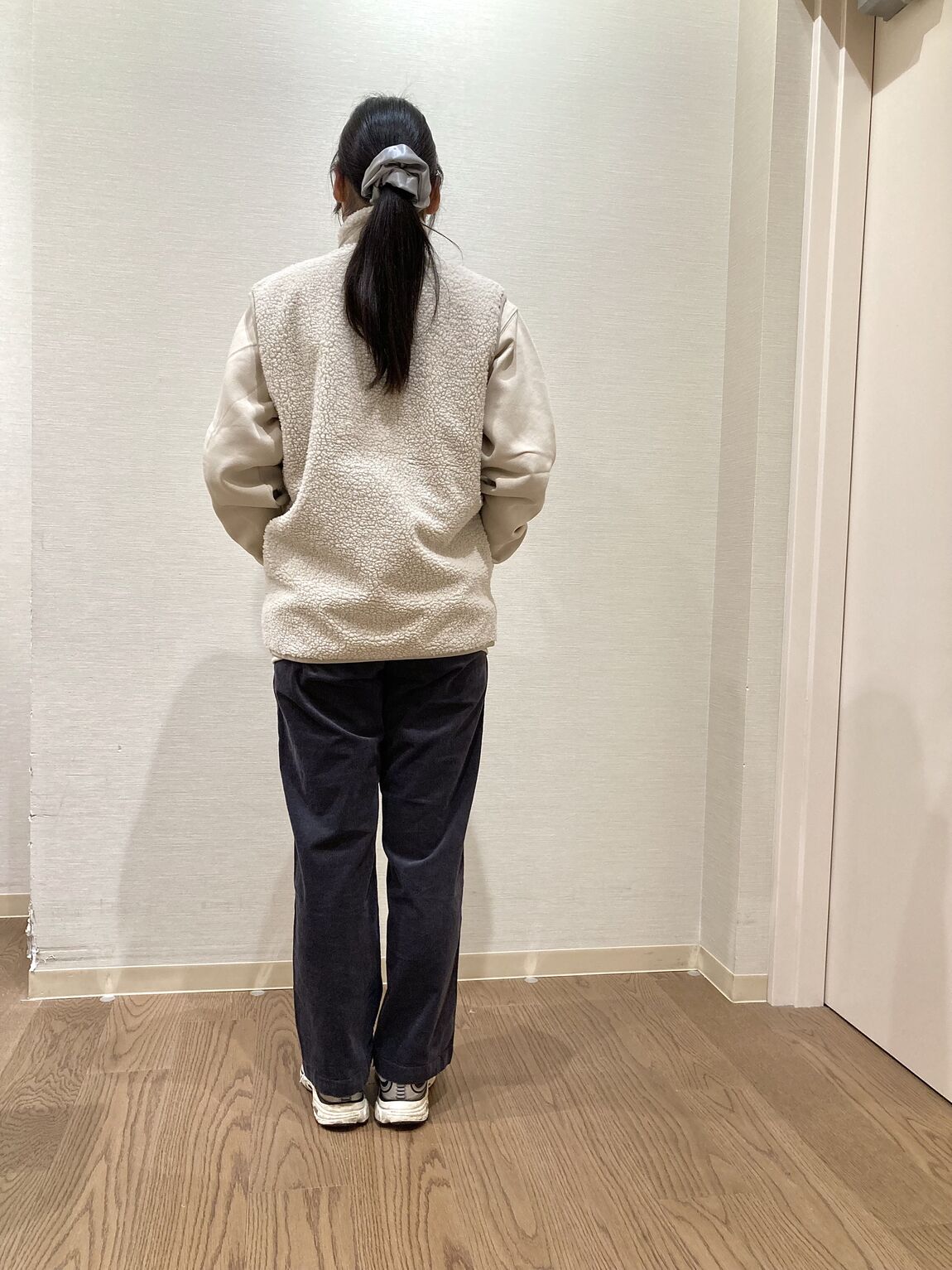 ベージュのスウェットシャツとベージュのボアベストを着用した女性　