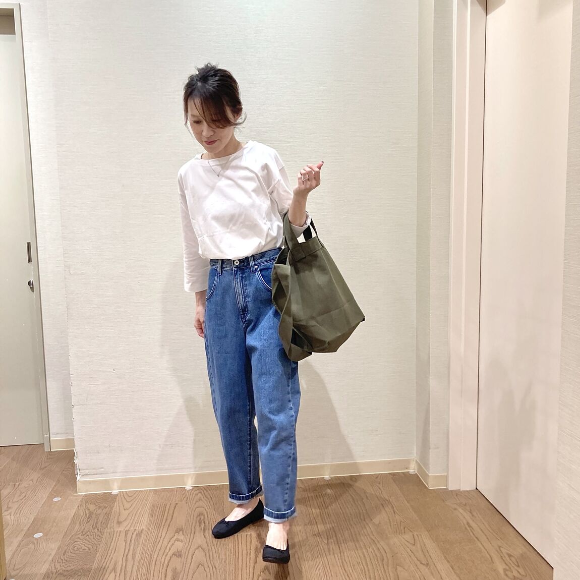 白いボートネックシャツにデニムを着用した女性