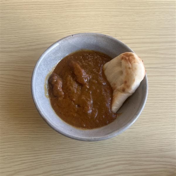 ナンをカレーに付けている画像