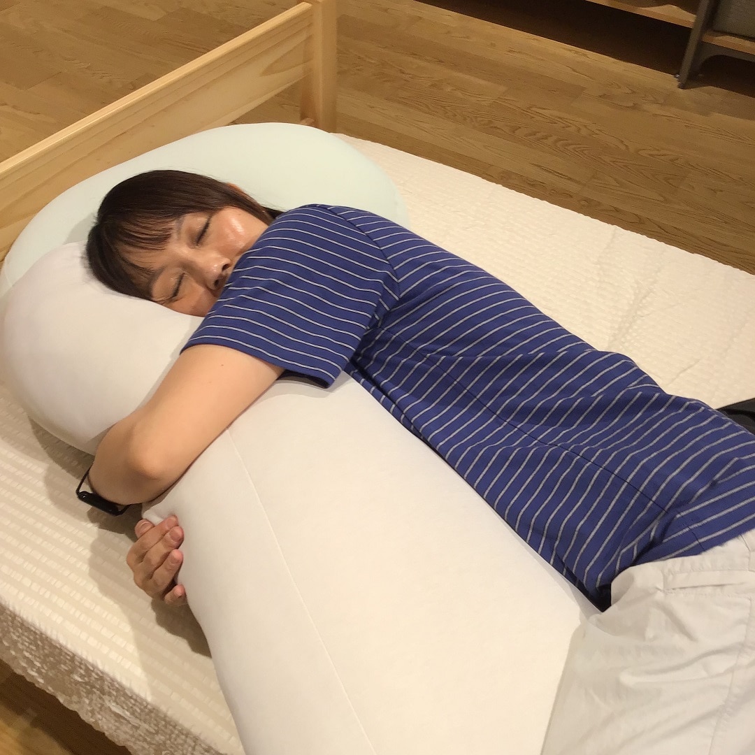 スタッフがひんやりシリーズの抱きまくらを抱いて寝ている写真