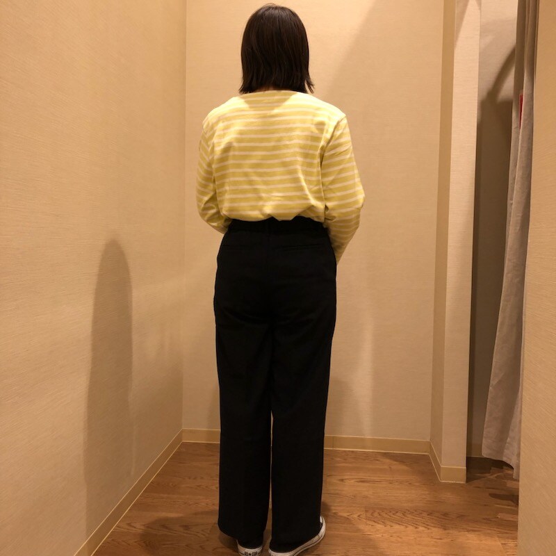 黄色いボーダーのトップスとネイビーのボトムスを着用した女性の後ろ姿の写真