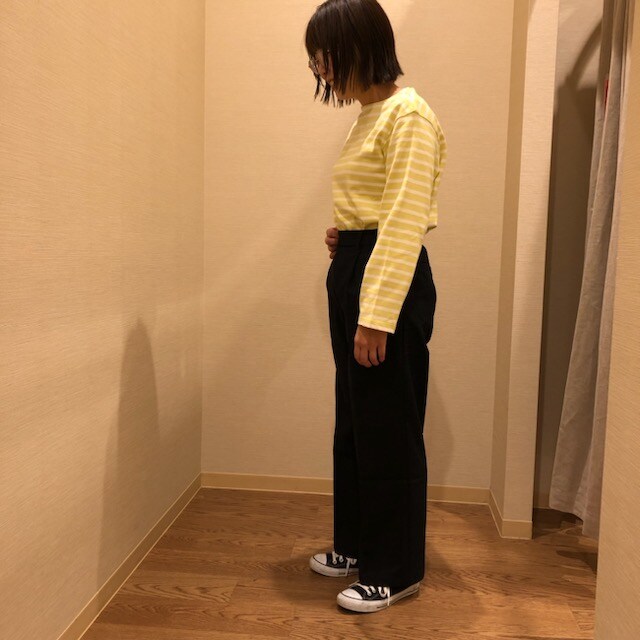黄色いボーダーのトップスとネイビーのボトムスを着用している女性の横からの写真