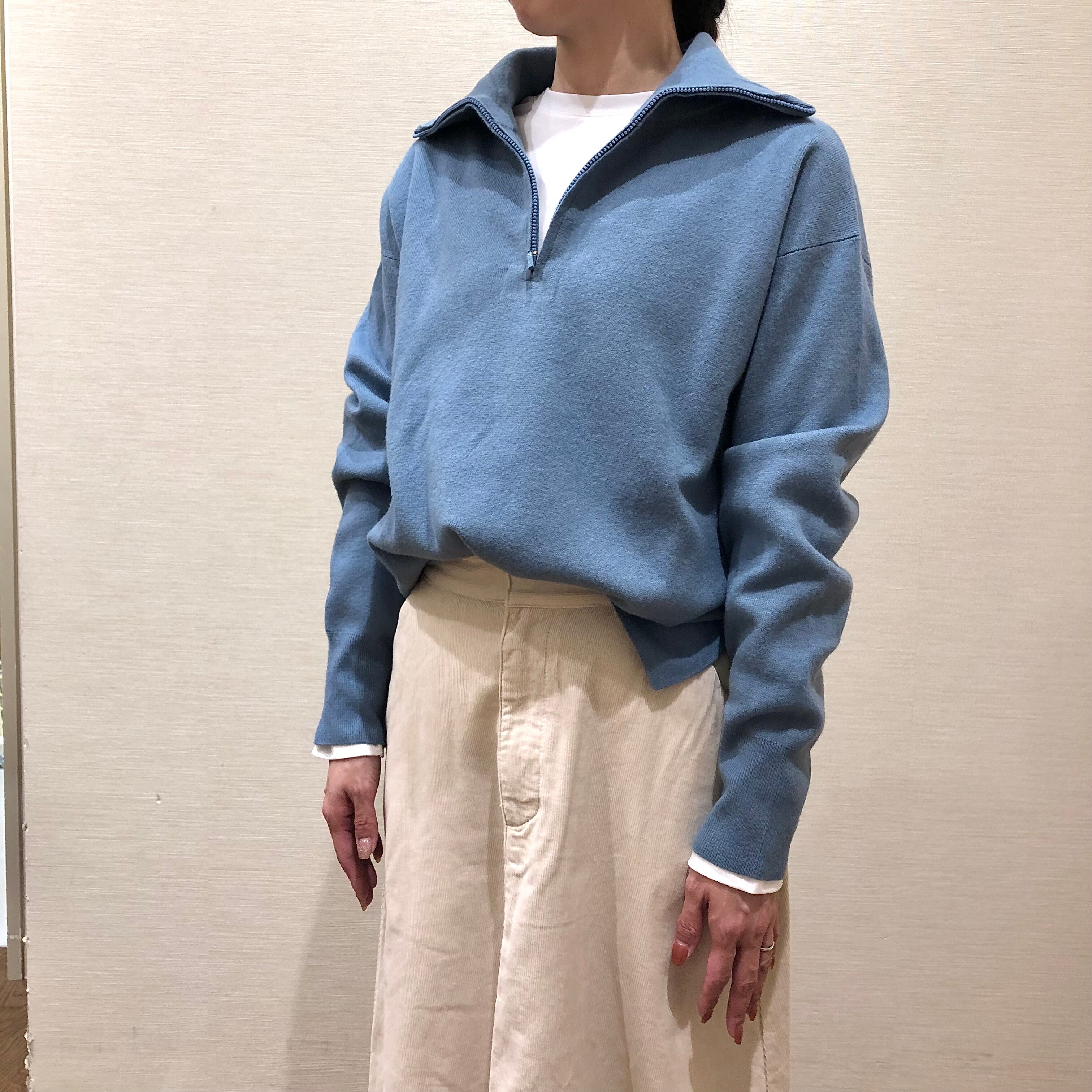 青いセーターと白いスカートを着用した女性