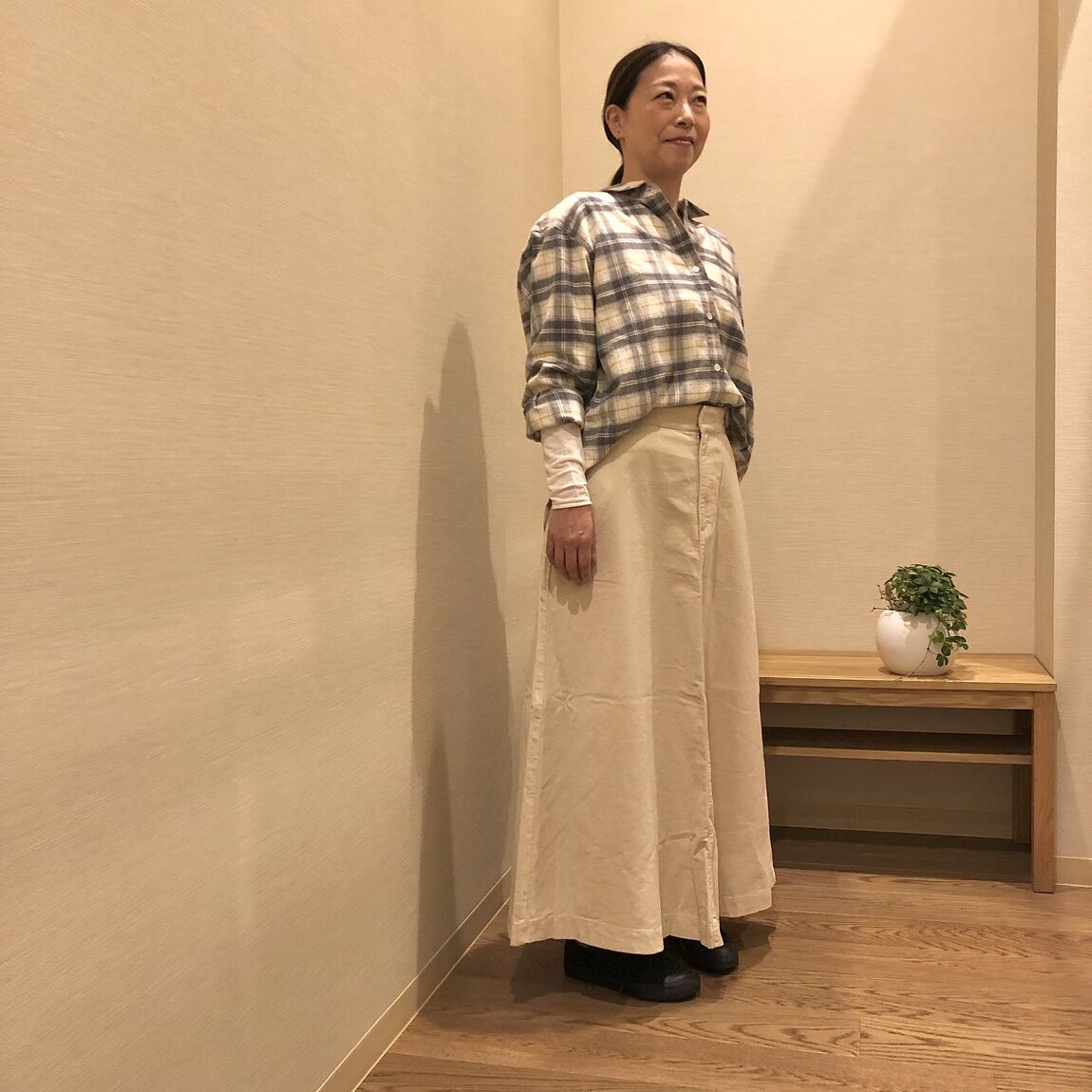 チェックのシャツと白いスカートを着た女性