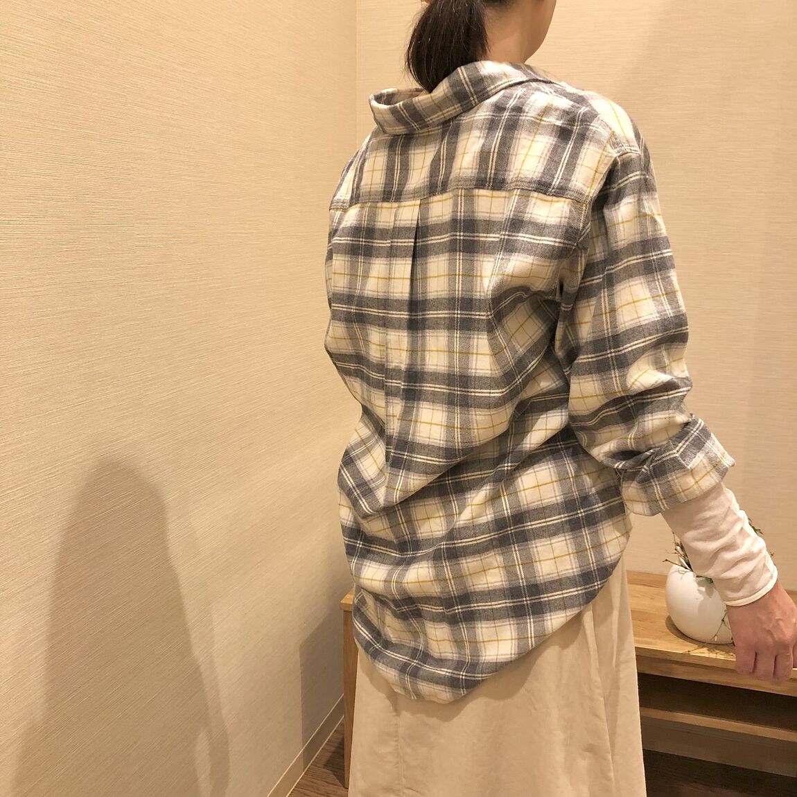 チェックのシャツと白いスカートを着た女性