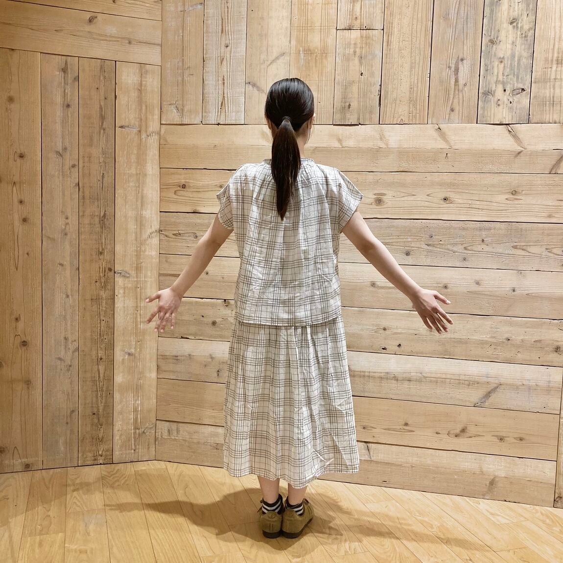 強撚スカートと強撚ブラウスを着用している。後ろ向きの女性。