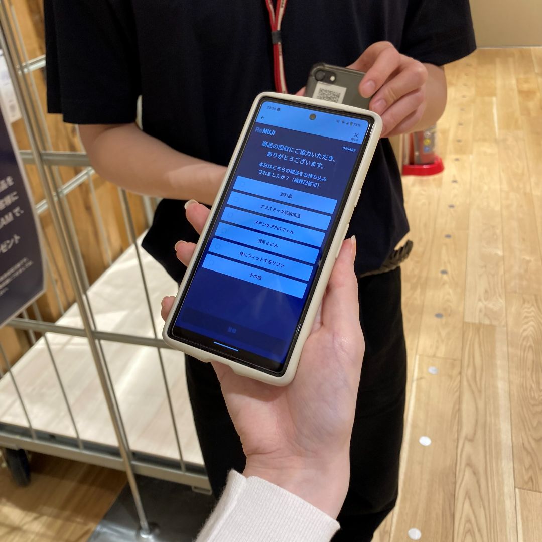 ReMUJIのポイント付与のためスタッフの持つバーコードをスキャンしている