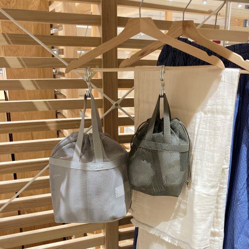 フックにかけられたグレーとカーキの立体メッシュ持ち手付き巾着