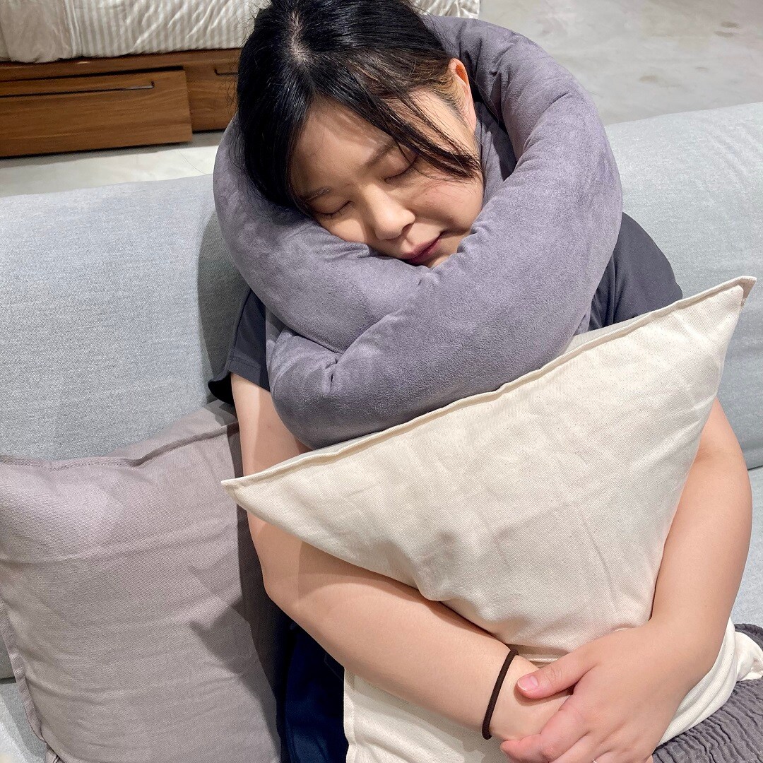 スタッフがループクッションを首に巻いて座っているところ