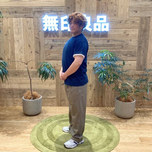 ネイビーのTシャツを着て斜め前を向いて立つ男性