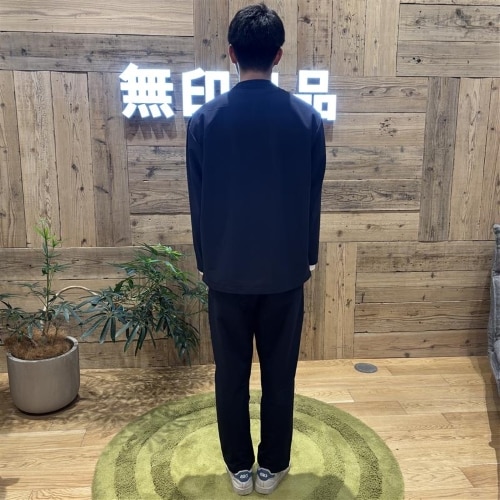 ネイビーのセットアップを着て後ろ向きに立つ男性