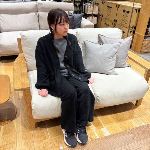 黒のセットアップのルームウェアを着てソファに座る女性