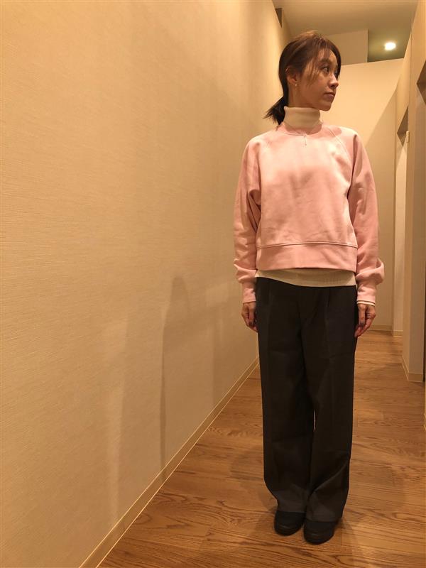 ピンク色のスウェットシャツとグレーのパンツを着用している女性の写真